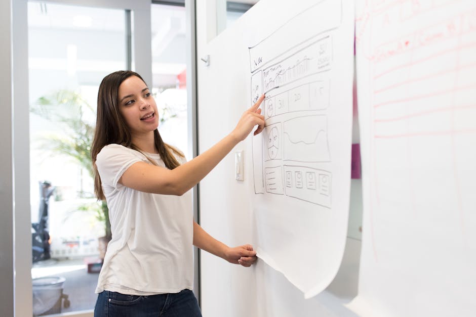 Confident young woman presenting a design on a whiteboard in a modern workspace.