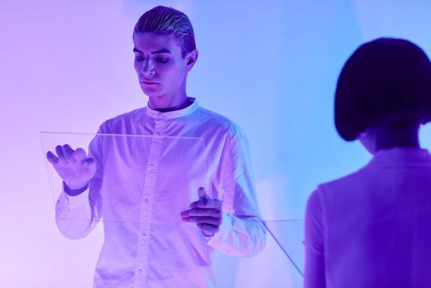 Two individuals interact with a transparent screen showcasing advanced technology in a vibrant setting.