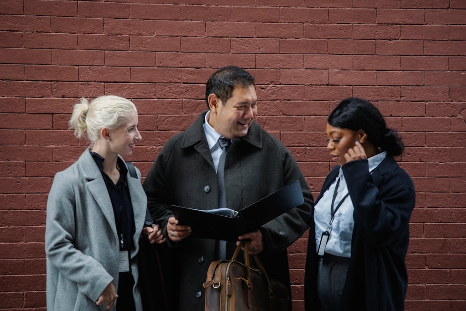 Smiling professionals discuss new strategies against a brick wall outdoors.