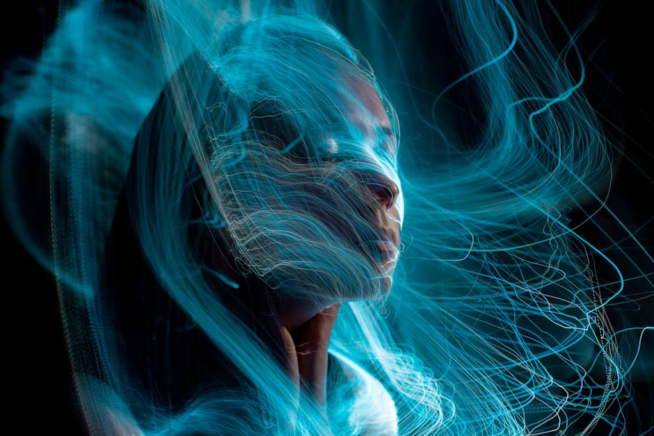 A surreal long exposure portrait featuring blue light trails around a woman's face, creating an ethereal effect.