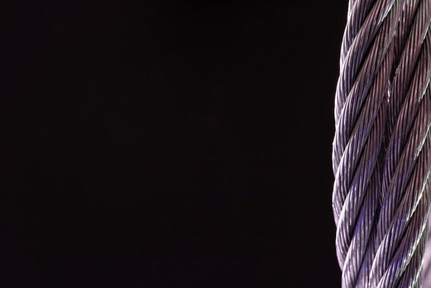 Detailed close-up of a silver twisted cable against a black background, perfect for industrial themes.