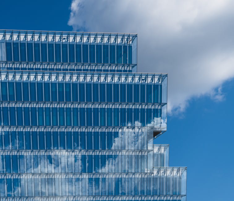 A striking image of a modern glass building reflecting the blue sky and clouds, showcasing architectural elegance.