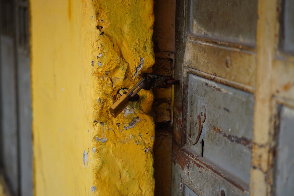 Close-up of a locked weathered metal door and textured yellow wall, symbolizing security.