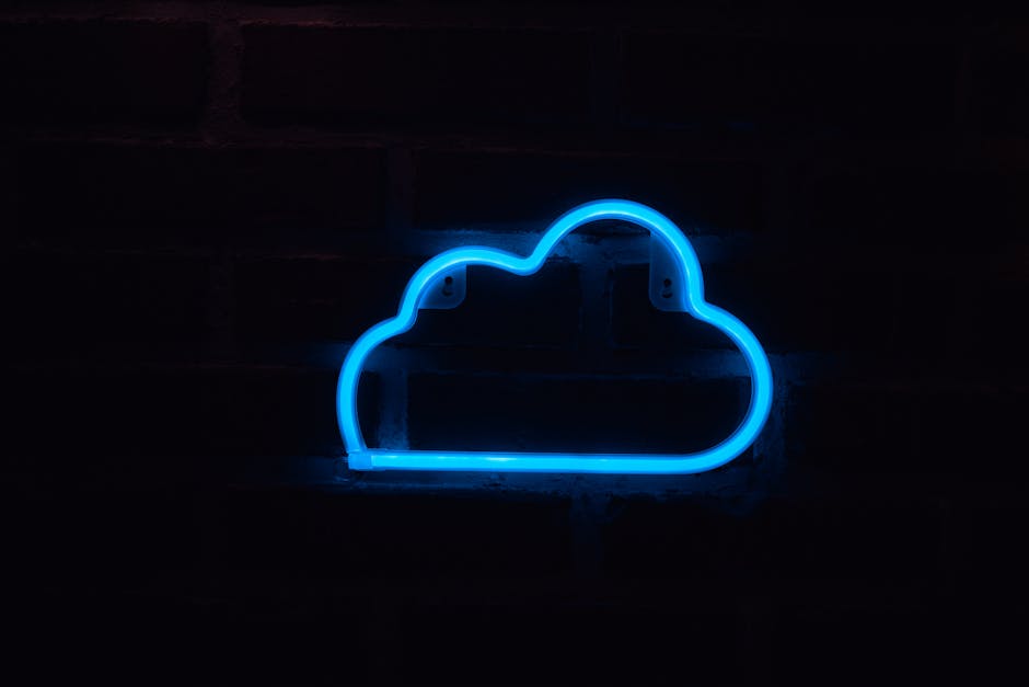 A bright blue neon cloud sign glowing against a dark brick wall background.